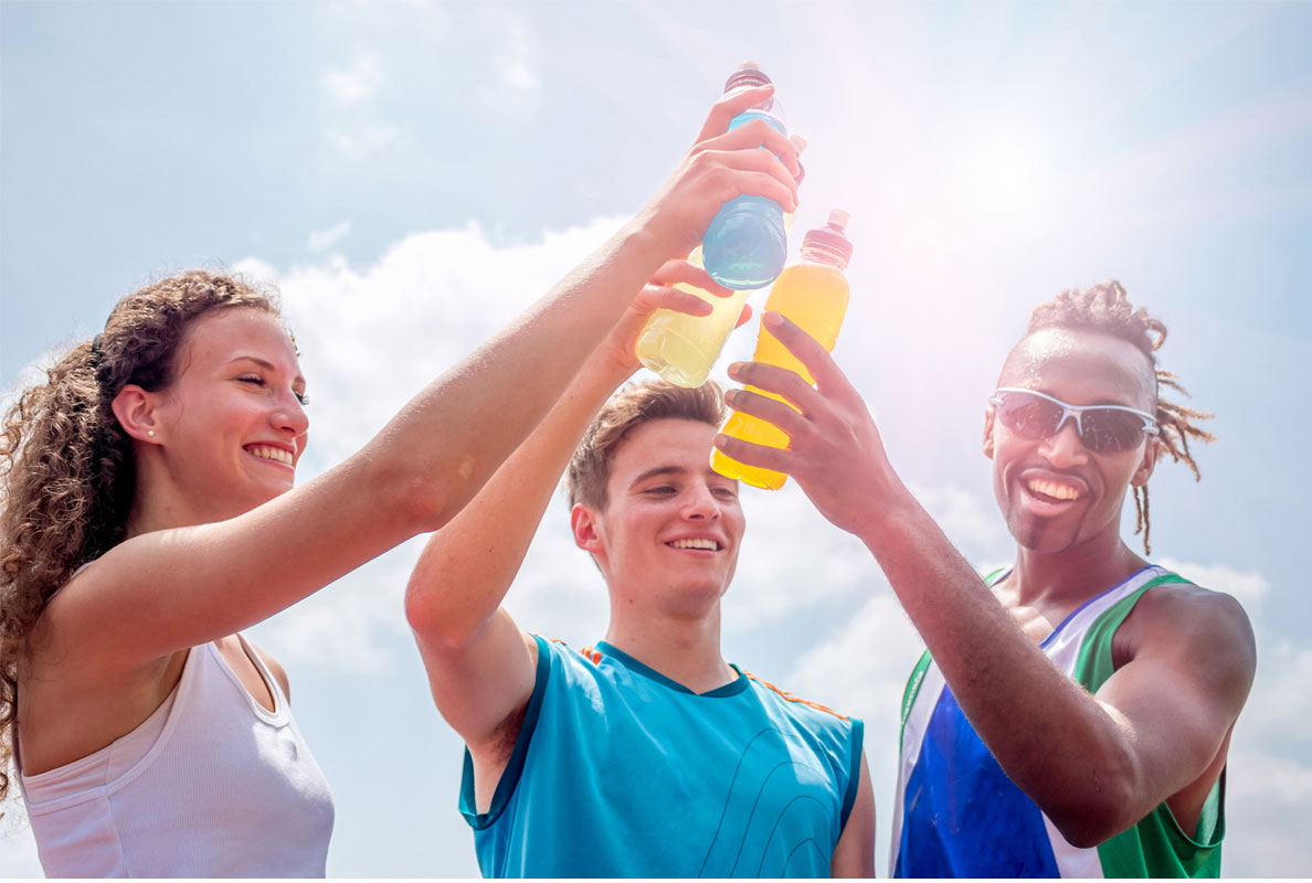 Three sportsmen toasting with water bottles on a sunny day