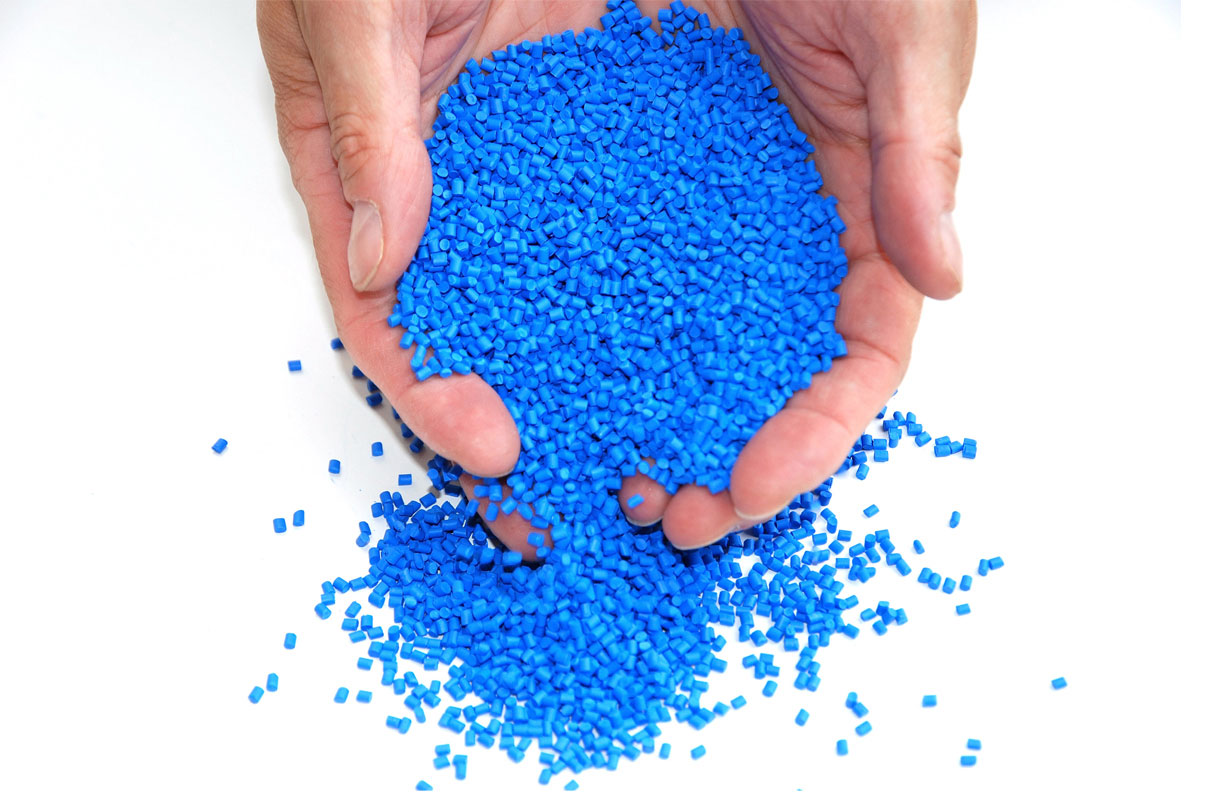 Two hands holding bright blue plastic particles